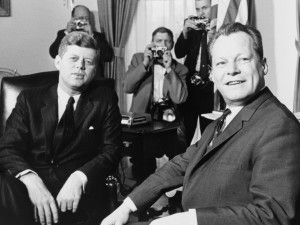 Willy Brandt sitzt neben US-Präsidenten John F. Kennedy im Weißen Haus. Fotografie in Schwarz-Weiß aus dem Jahre 1961.